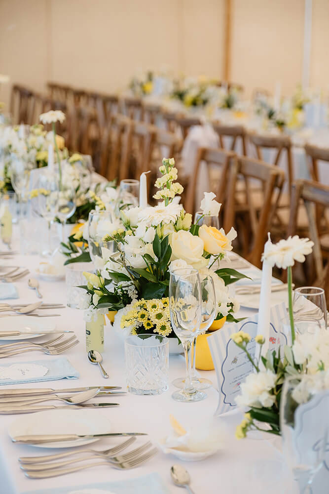 Ground-level floral arrangement in buttery yellows, creams and whites lining the ceremony aisle