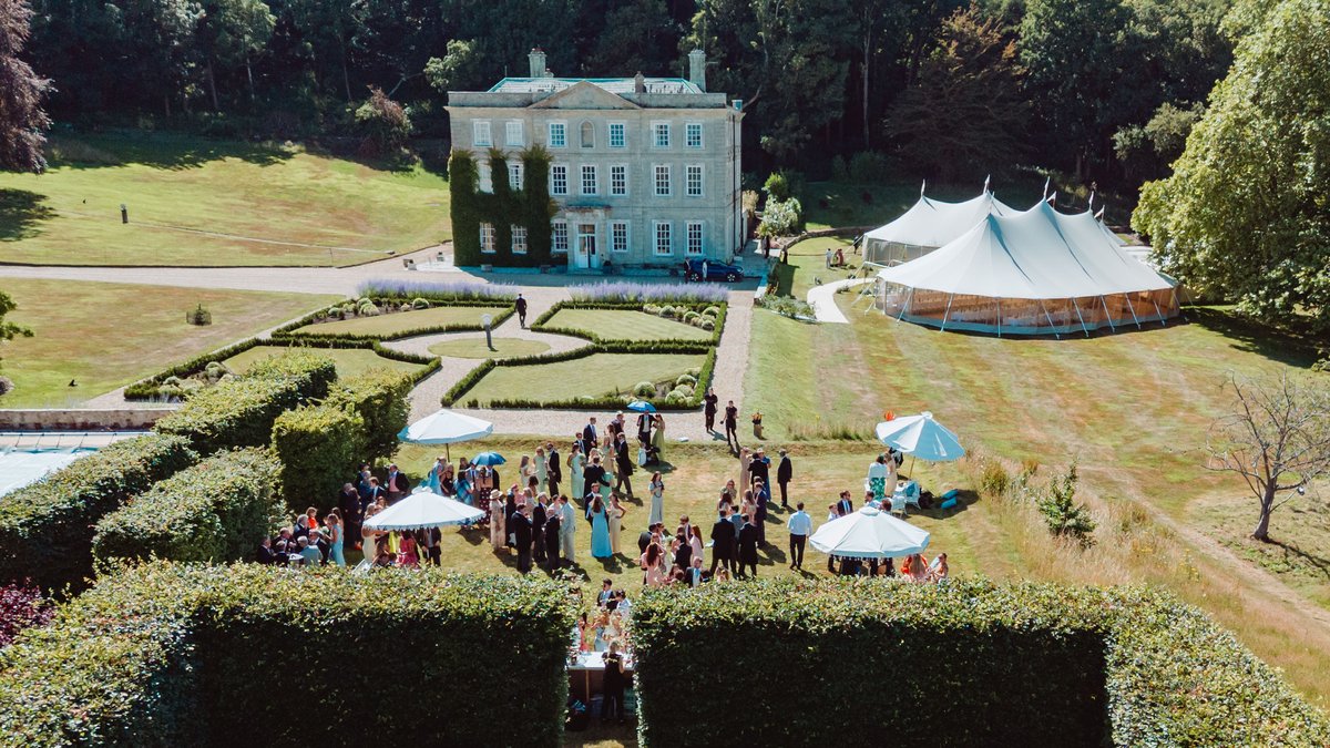Aerial view of guests on the lawn with the ivy-clad manor and sailcloth tents behind, Isle of Wight