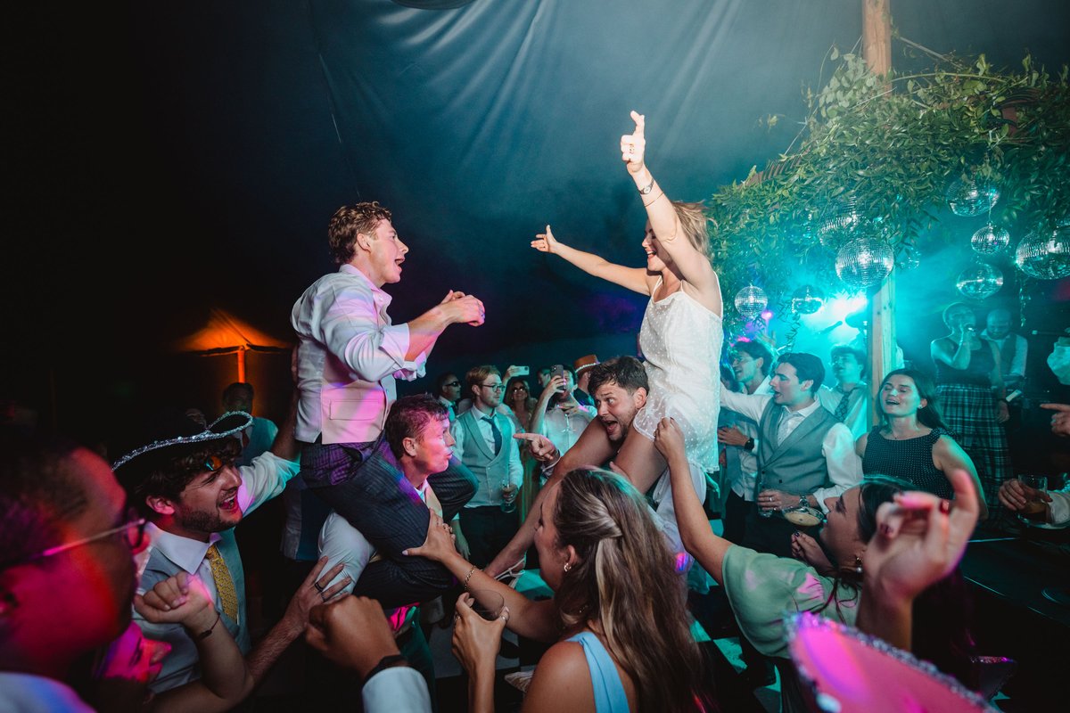 Bride and groom hoisted onto shoulders above the dancefloor among glittering disco balls