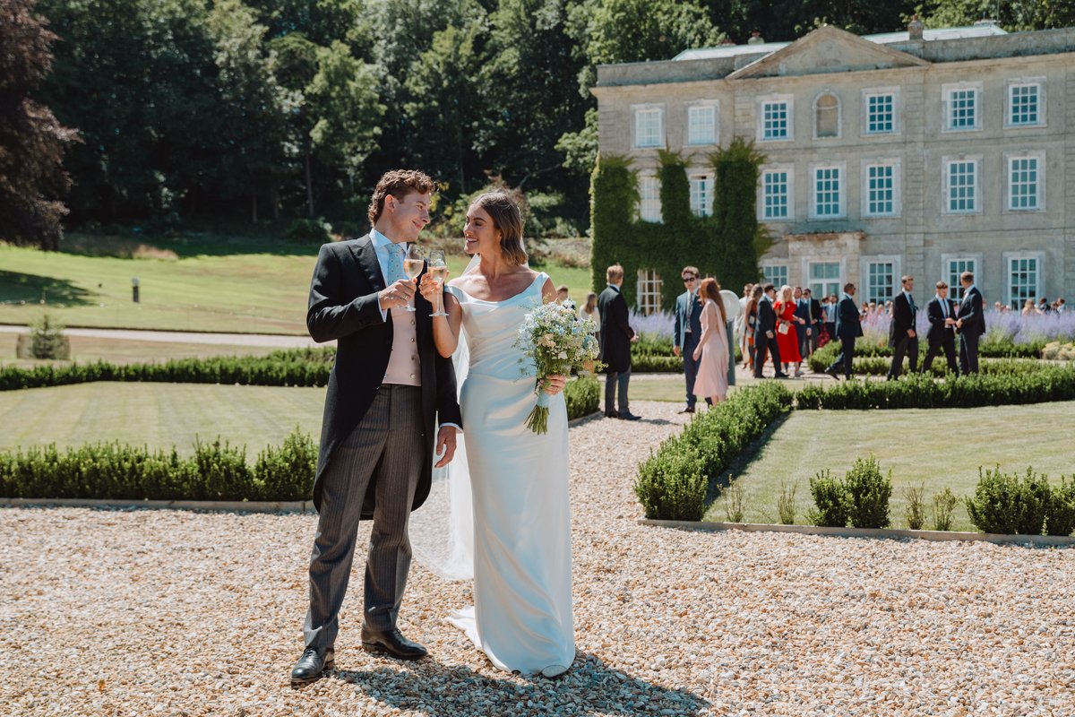 Bride and groom toasting with champagne on the gravel in front of Gatcombe Estate