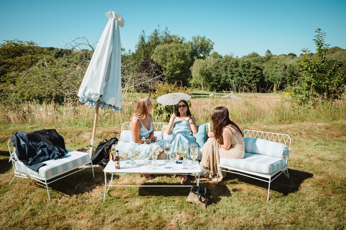Guests relaxing on striped garden sofas with a paper parasol in the summer sun