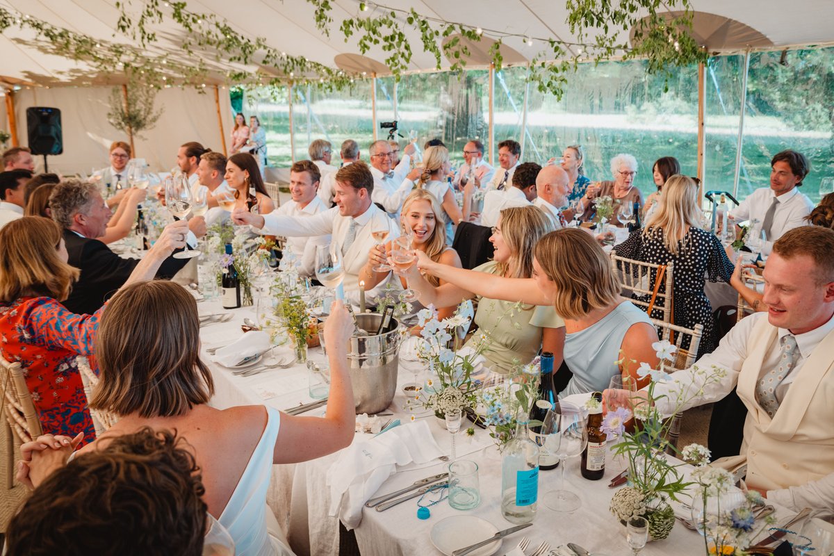 Guests raise their glasses across long candlelit tables in the sailcloth dining tent