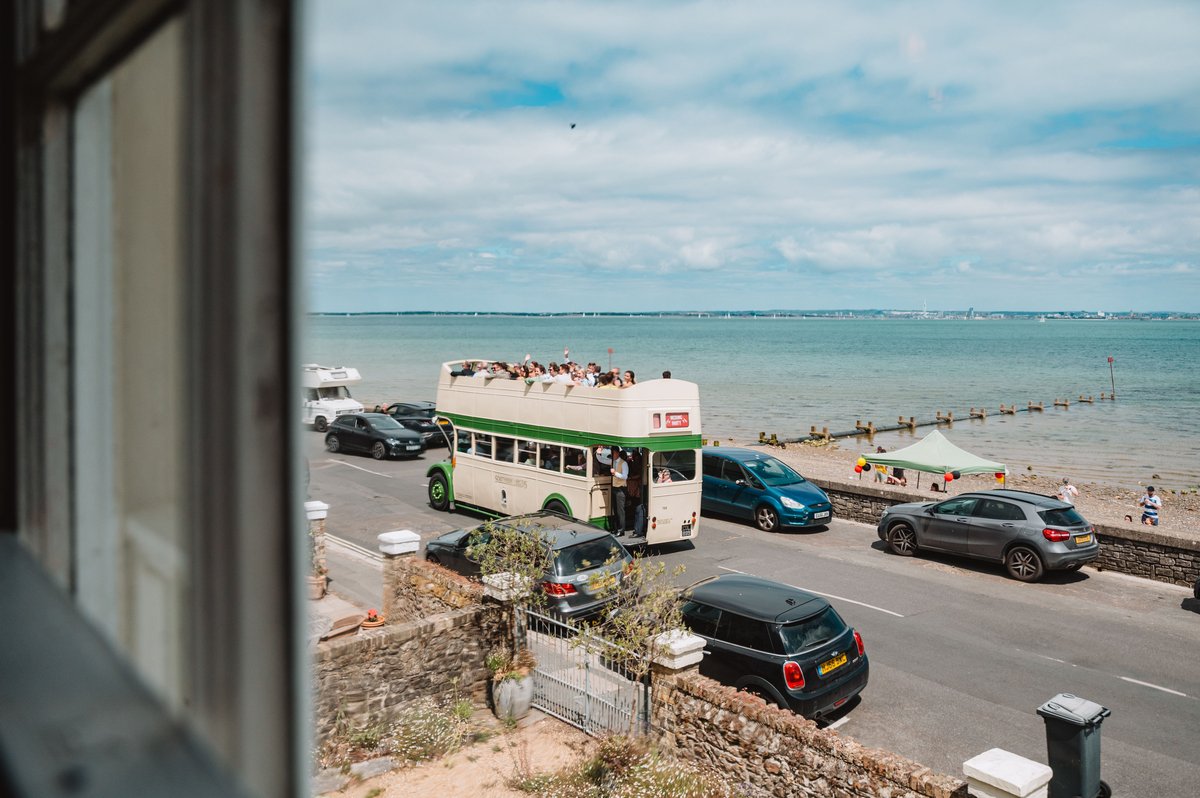 Vintage open-top double-decker bus packed with waving guests on the Seaview seafront, Isle of Wight
