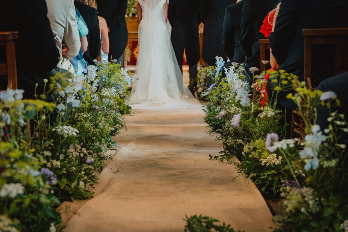 Hessian aisle runner lined with delphinium, ammi and scabious as the bride reaches the altar