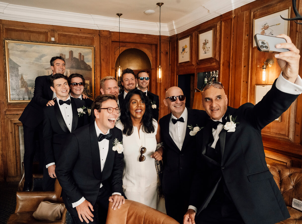Groomsmen and bride crowd in for a selfie in a wood-panelled lounge at The Towers