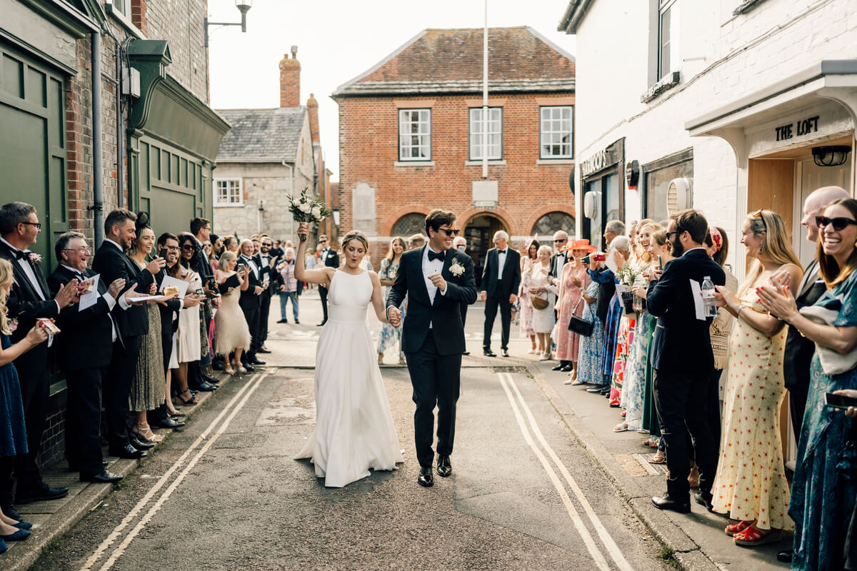 Bride and groom walk through a tunnel of clapping guests on a Yarmouth high street
