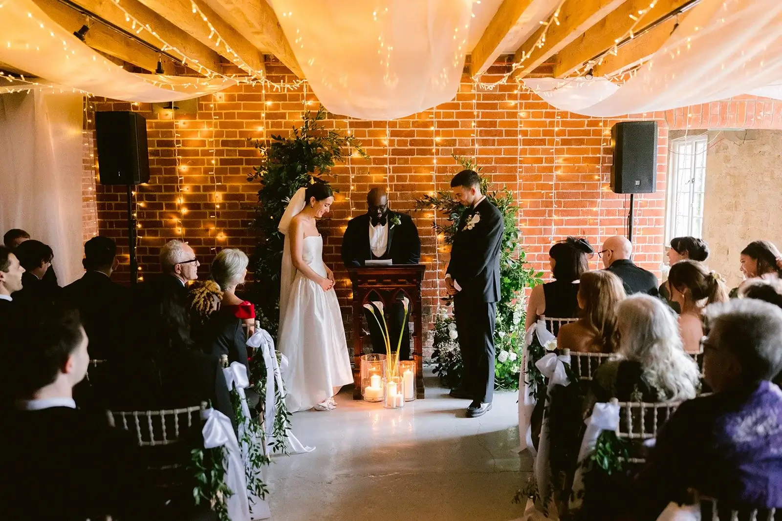 Black and white shot of the live band performing against the exposed brick wall of the reception barn