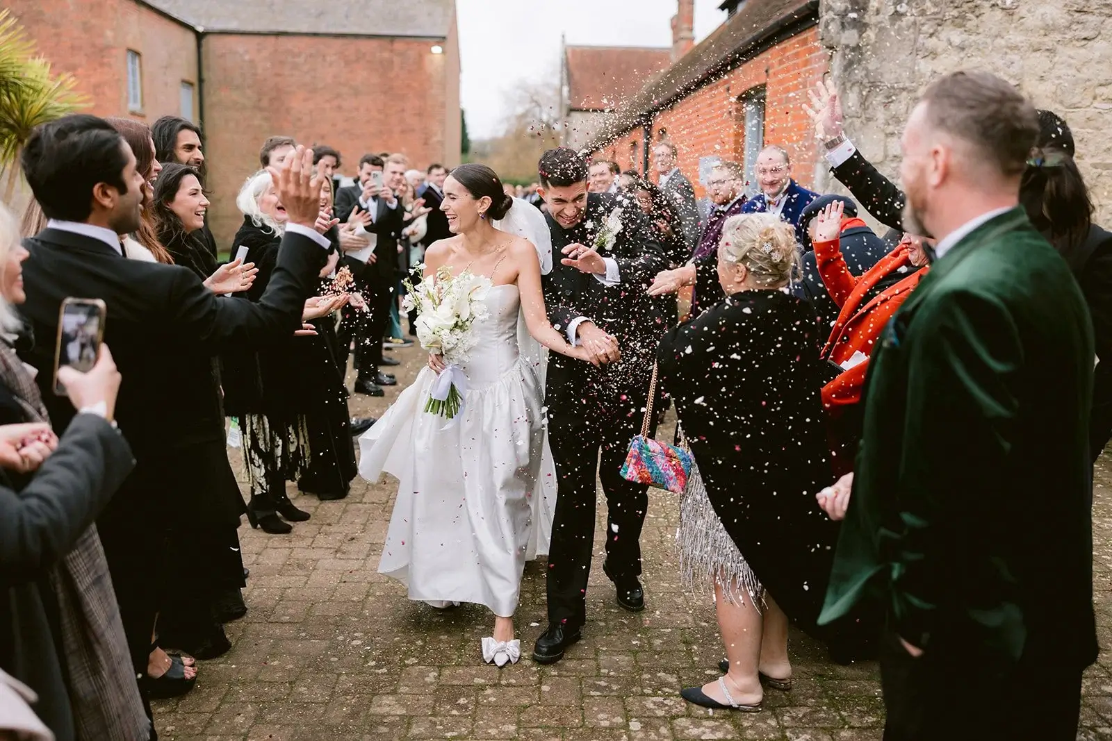 Fiona and Liam exchanging vows at the altar of a candlelit brick ceremony barn, greenery either side