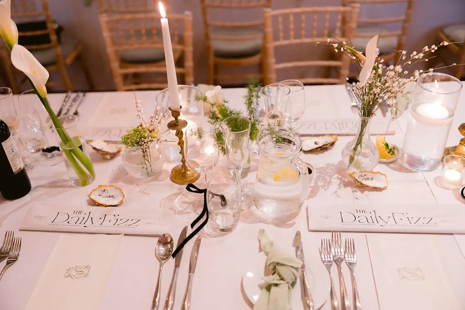 Place setting detail with hand-lettered name cards on oyster shells reading Fiona and Liam