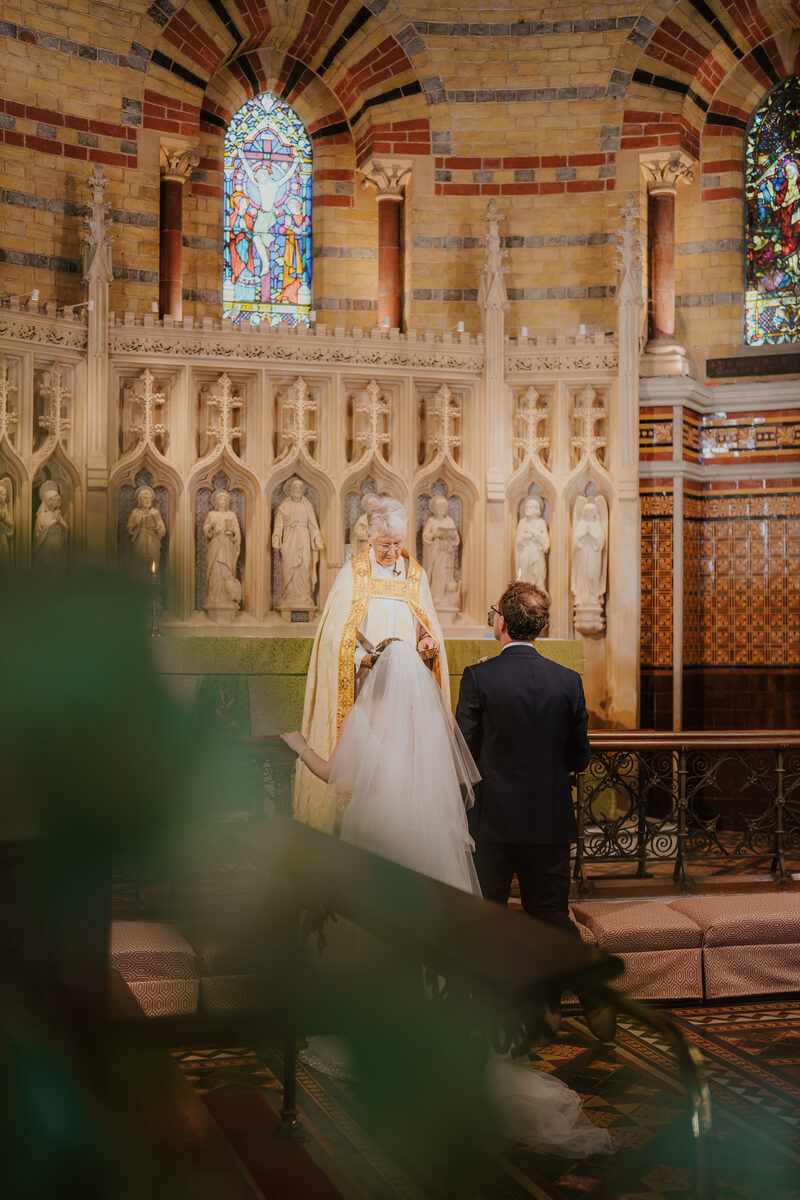 Bride and groom standing at the altar before the vicar inside Holy Trinity Church Cowes
