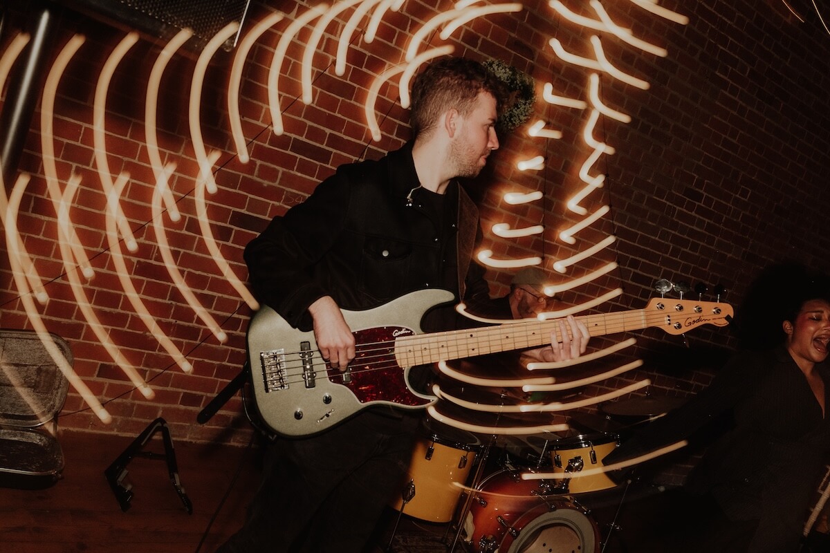 Long-exposure shot of the evening band's bassist mid-song, light trails swirling around him on the dance floor