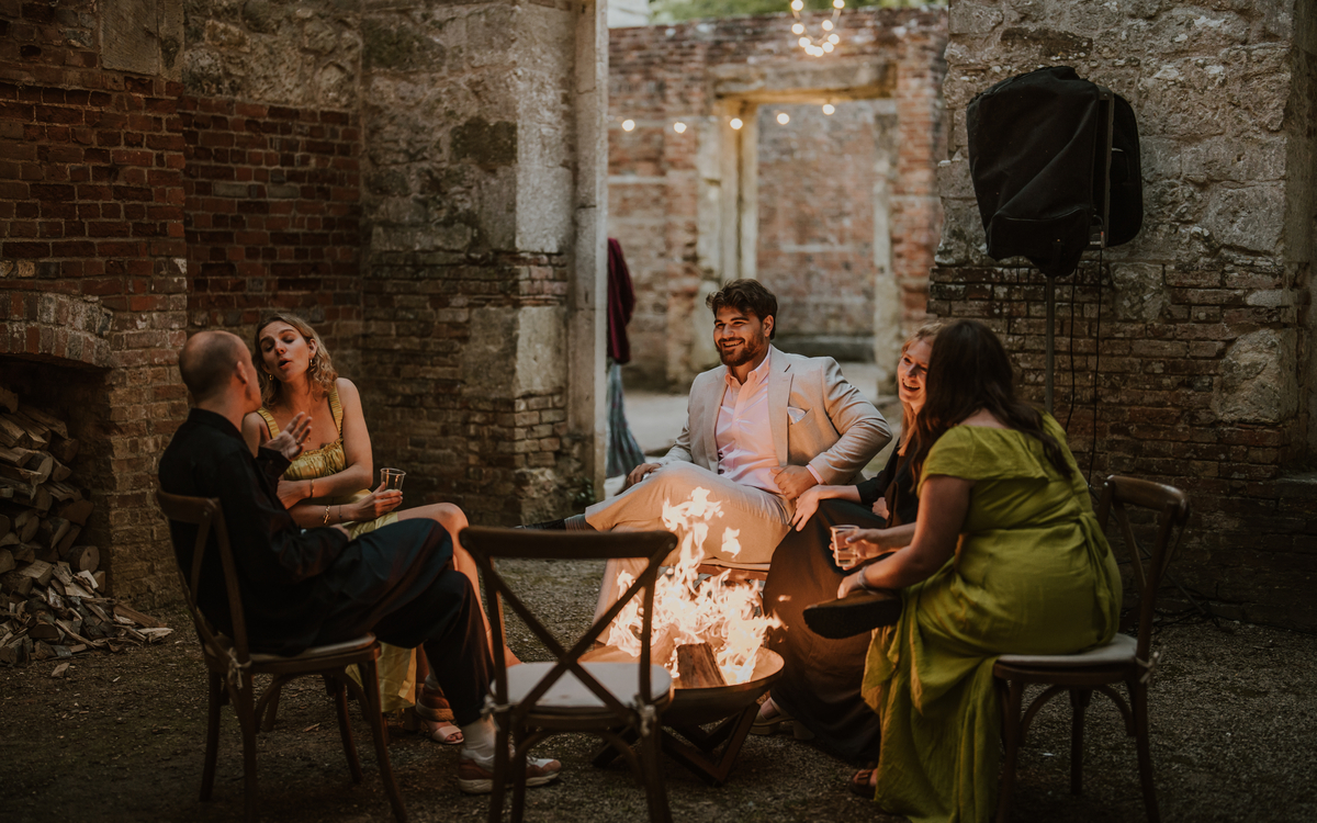 Guests chatting around an open fire pit inside the brick ruins at Appuldurcombe House