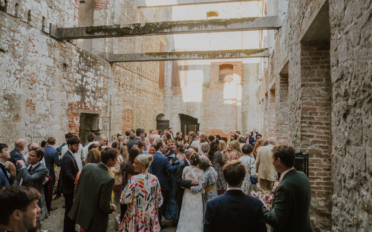 Guests mingling beneath open steel beams inside the stone ruins at Appuldurcombe House