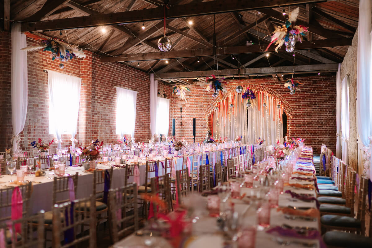 Reception tables set in the brick barn at Barton Manor