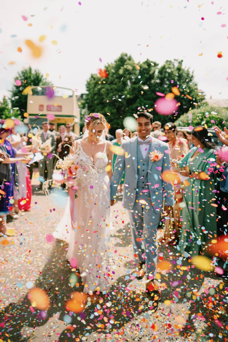 Lily & Ash walking through a shower of confetti