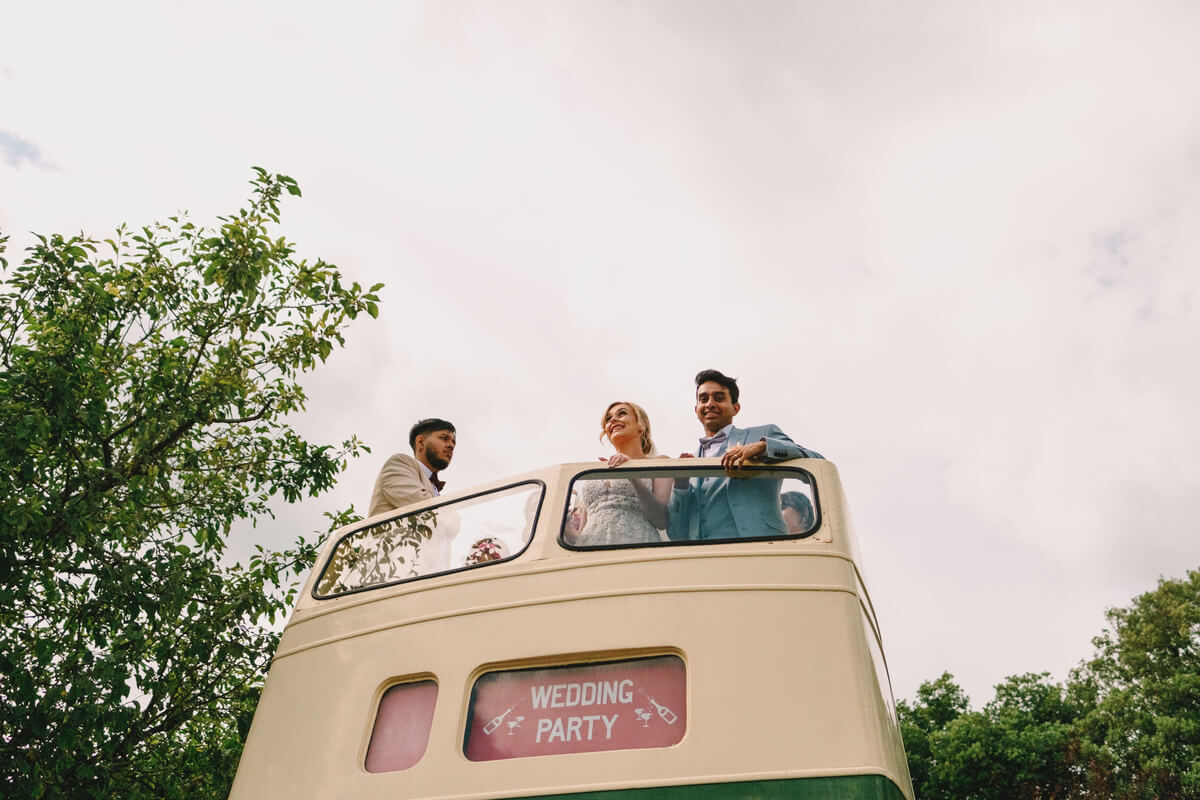 Wedding party aboard the open-top vintage bus at Barton Manor