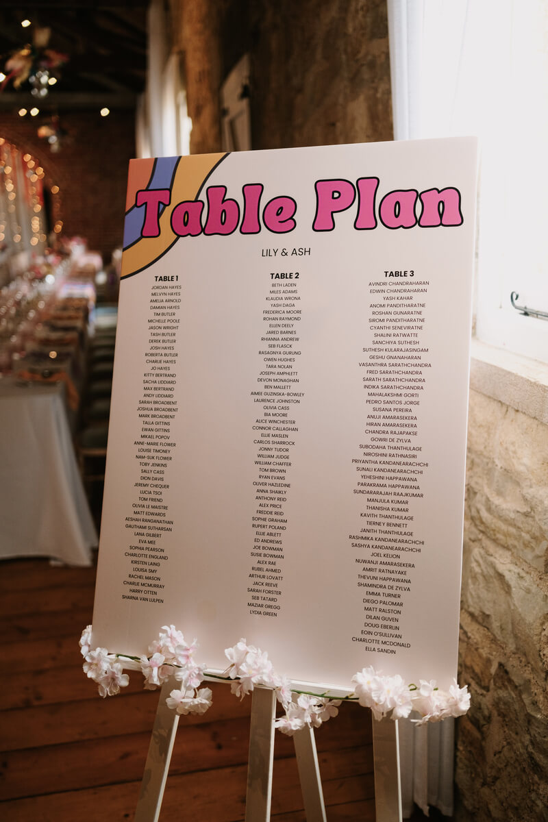 Retro rainbow wedding table plan in hot-pink bubble type