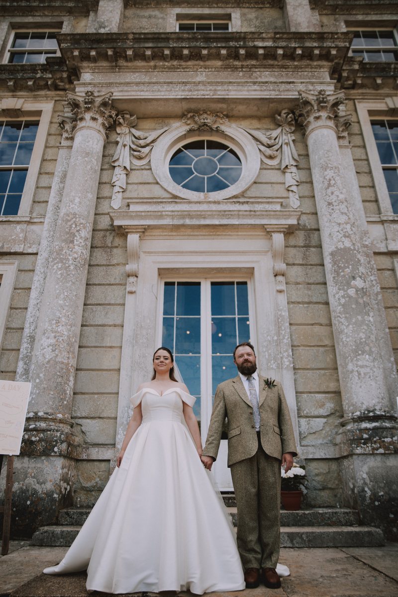 Rebecca and Russel hold hands beneath the grand carved doorway and oculus window of Appuldurcombe House, Isle of Wight