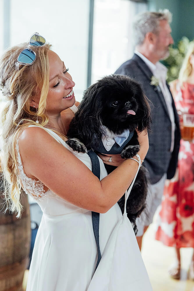 Rosie cuddling the couple's small black dog dressed in a matching bow tie and waistcoat at the reception