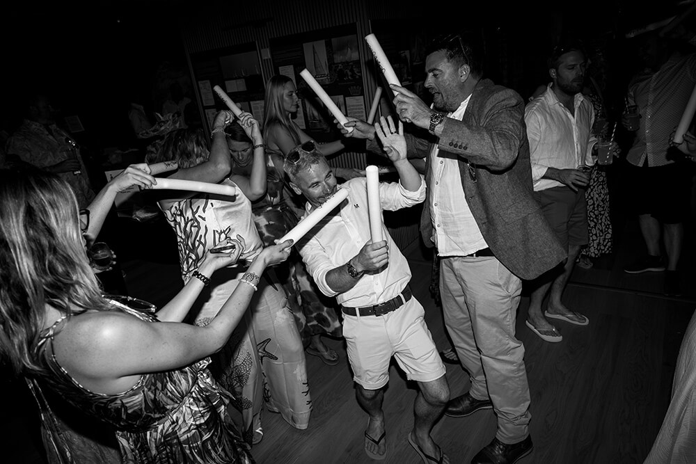 Guests dancing in the dark with light-up glow sticks raised overhead as the evening reception gets going