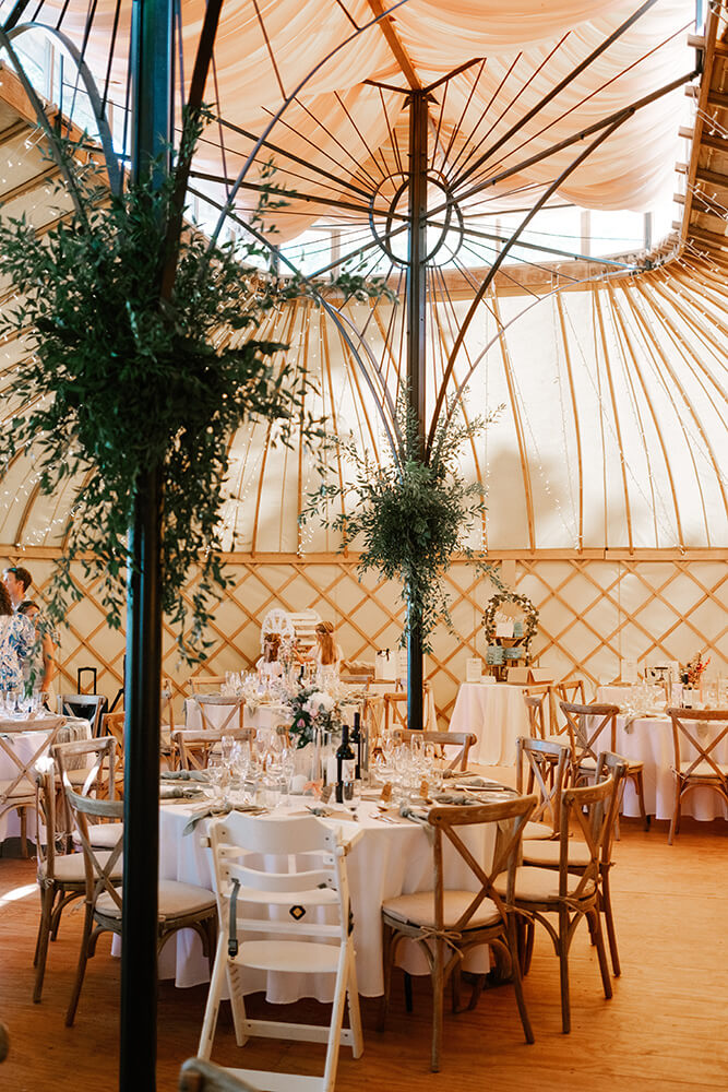 Candlelit yurt reception details: sage linen tables and wildflower blooms